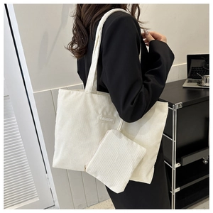 Detail of white corduroy tote bag set with FASHION label on model shoulder