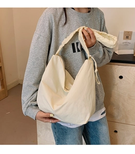 Detail of creamy white crescent shoulder bag with ruched strap texture and zipper
