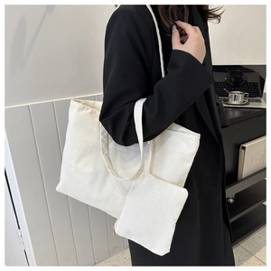 Detail view of white corduroy tote bag set with matching zipper pouch and logo label