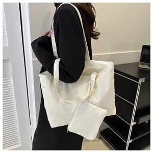 Detail view of off-white corduroy tote bag set with a small clutch and fashion label