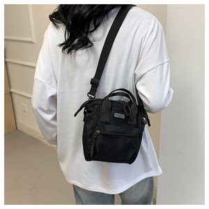 Détail d'un sac bandoulière en toile noire avec logo S SPORT et sangle réglable