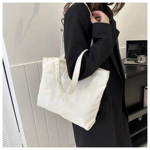 Close-up of a white corduroy tote bag with Fashion patch shown in a lifestyle office setting
