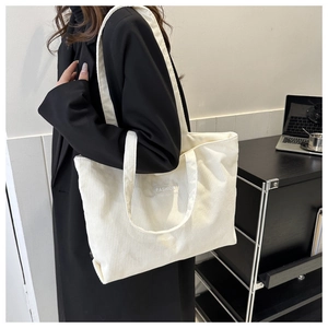 Close-up of white corduroy tote bag featuring a Fashion label on minimalist surface