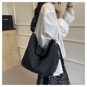 Detail of a black nylon crossbody bag featuring stylish pleated shoulder strap design