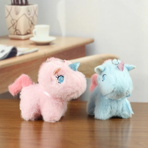 Cute pink and blue plush unicorn keychains with sequin horns on a warm wooden desk