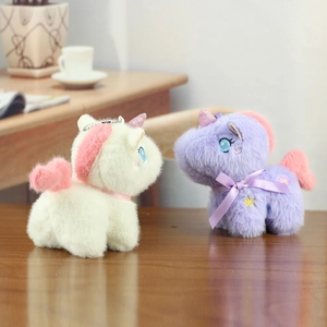 Detail of plush unicorn charms with glitter horns and ribbon bows on a wooden surface