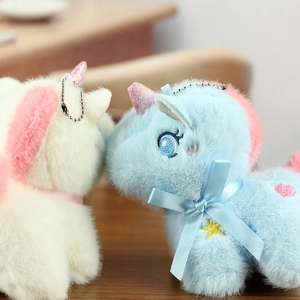 Close-up of soft plush unicorn pendants with blue star embroidery and satin bows