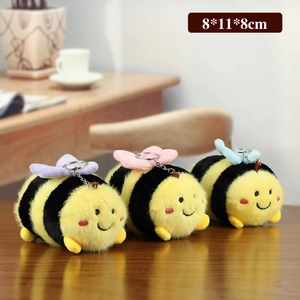 Three cute plush bee keychains with colorful wings on a cozy wooden surface, 8x11x8cm
