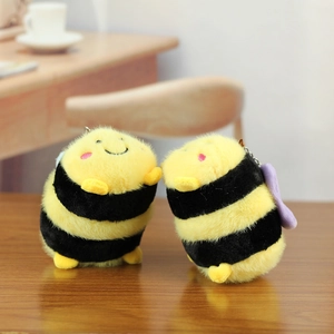 Close-up of cute plush bee charms with yellow and black fur on a wooden table