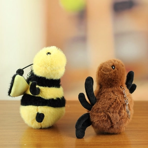 Plush bee and beetle insect keychains with soft faux fur and metal ring on wooden surface