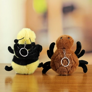 Plush bee and spider keychain set with soft faux fur and metal ring on wooden table