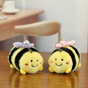 Close-up of cute plush bee keychains with colorful wings on a warm wooden table