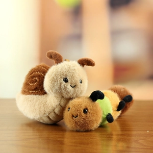 Detailed plush texture of miniature snail and caterpillar bag charms on a wooden surface