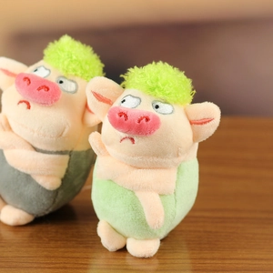 Detail von grünen Plüschschwein-Anhängern mit süßen Ausdrücken und Stickereien