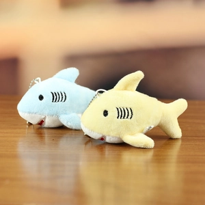 Cute plush shark and whale keychains in light blue and yellow on a wooden desk