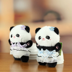 Detail of cute giant panda plush keychains with purple and blue bows on wooden desk