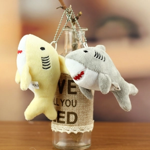 Detail of plush shark keychains in grey and yellow with metal bead chains on a bottle