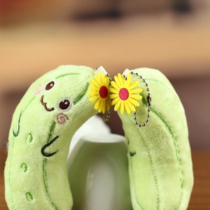 Nahaufnahme von Plüsch-Gurken-Schlüsselanhänger mit Stickerei und gelber Gänseblümchen