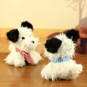 Close-up of white plush Westie dog keychains with striped scarves on a wooden surface