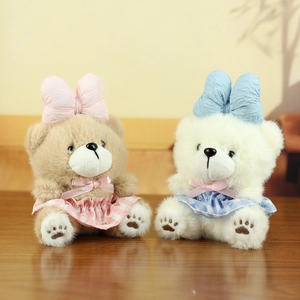 Close-up of cute plush bears with plaid aprons and large bows on a wooden surface
