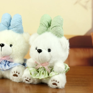 Close-up of white plush teddy bear charms with large colorful bows and plaid dresses