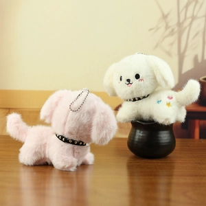 Detail of pink and white plush puppy keychains with studded collars and heart embroidery