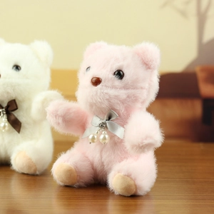 Macro detail of plush teddy bear with satin ribbon bow and pearl pendant accessories