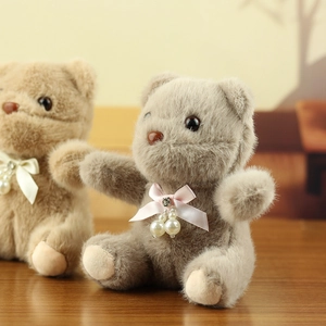 Detail of plush bear pendants with pearl rhinestone bows on a warm wooden surface