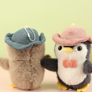 Detail of plush penguin keychains featuring corduroy hats and metal bead chains