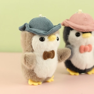 Close-up of cute penguin plush keychain featuring soft grey fur and blue corduroy hat