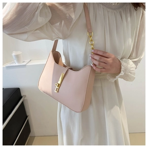 Close-up of light pink underarm bag with gold metal clasp and leather chain strap