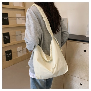 Detail of minimalist beige nylon crossbody bag featuring drawstring pleated texture