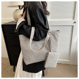 Detail of grey corduroy tote bag showing fashion lettering and matching small pouch