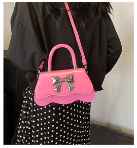 Détail du sac à main rose à bords ondulés avec nœud argenté, porté par le mannequin