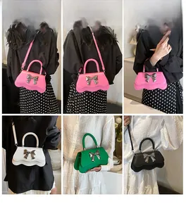 Détails de petits sacs bandoulière avec nœud métallique et design à bords ondulés