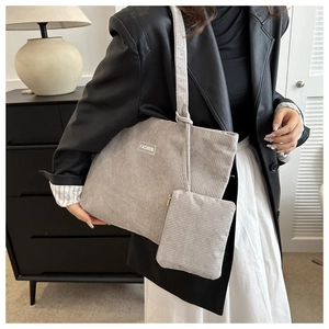 Grey corduroy tote bag detail with 'FASHION' label and matching pouch on a model