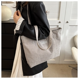 Close-up of light gray corduroy tote bag showing soft ribbed texture and fashion label