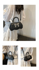 Détail du sac à main en cuir noir avec un grand nœud en métal argenté et bordure ondulée