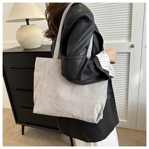 Detailed view of light gray corduroy tote bag showing striped texture on a model