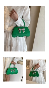 Détail du sac vert brillant avec bords festonnés et nœud métallique argenté chic