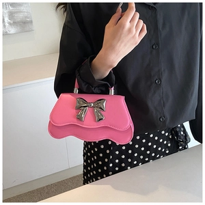 Gros plan du sac à main rose avec nœud métallique argenté et base plissée ondulée