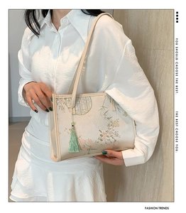 Detail view of a beige silk-texture tote with Chinese floral print and green tassel