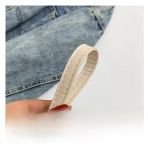 Detail of the cream leather shoulder strap showing fine stitching and metal loop