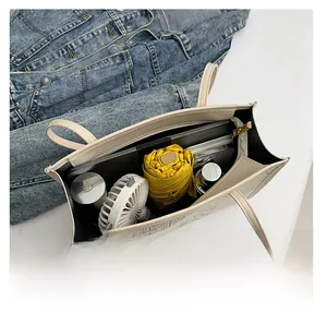 Top view of cream tote bag interior showing large capacity with a laptop and umbrella