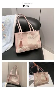 Detailed close-up of pink silk tote bag featuring floral embroidery and tassel charm