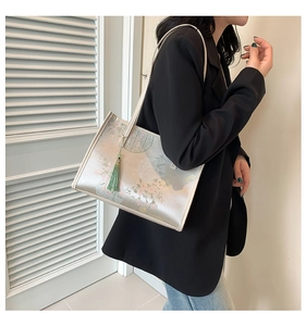 Close-up of silk-textured tote bag with traditional floral bird print and green tassel