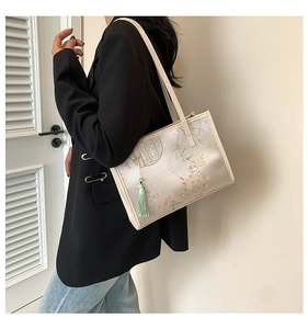 Detailed close-up of a silk tote bag with Chinese floral patterns and green tassel detail
