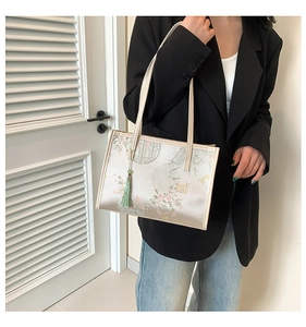 Detailed shot of silk satin tote bag with floral patterns and a long green tassel charm