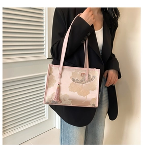 Detail of floral jacquard tote bag with elegant tassel charm and pink leather straps
