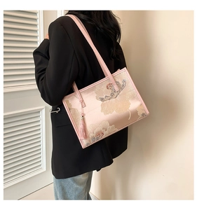 Detail of pink floral embroidery tote bag with silk texture and decorative tassel